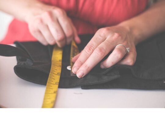 hands measuring a garment with a measuring tape