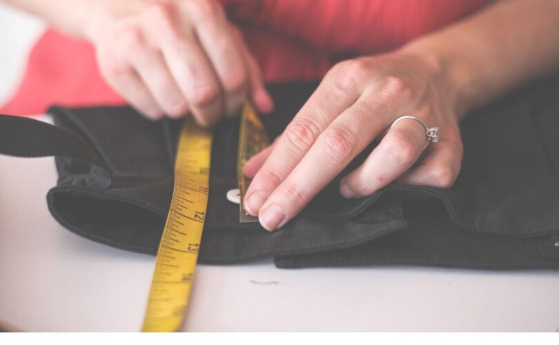 hands measuring a garment with a measuring tape